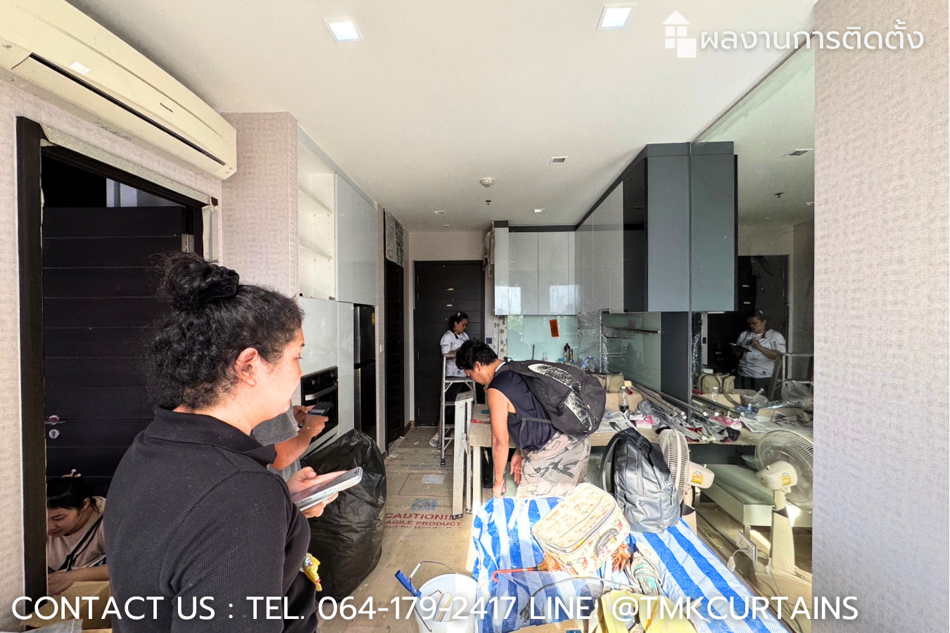 บรรยากาศการปฏิบัติงานติดตั้งวอลเปเปอร์ห้องนั่งเล่นคอนโด มีการปูผ้าใบกันเปื้อนอย่างแน่นหนาเพื่อป้องกันความเสียหาย